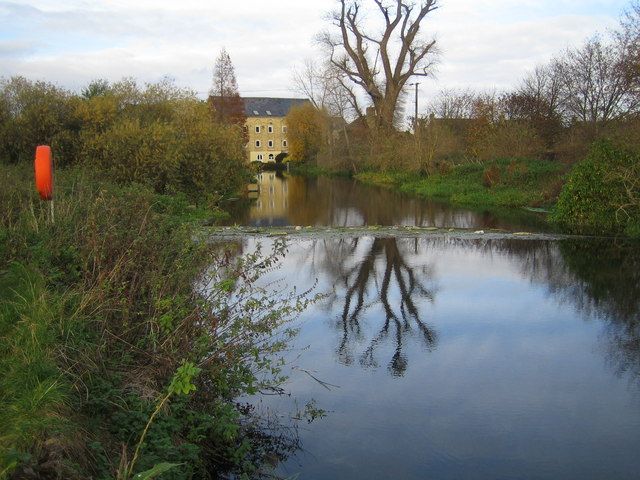 Calm river ivel with Mill in the distance and lone tree reflected in the water